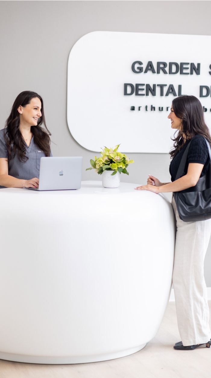 Dental office reception with smiling staff interaction.